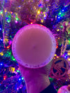 Round white object held in front of a colorful Christmas tree with lights and decorations.